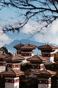 there are many white and red buildings on the mountain side with mountains in the background