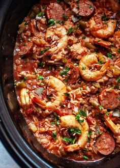 a crock pot filled with shrimp, sausage and rice