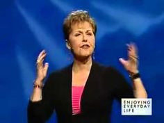 a woman standing in front of a blue background holding her hands up to the side