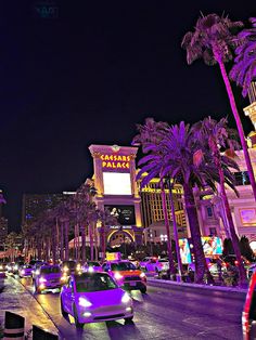 cars are driving down the street in las vegas at night with palm trees on both sides