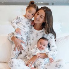 a woman and her baby are sitting on a bed in matching pyjamass