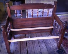 an old wooden bed frame sitting on top of a wooden floor next to a brick wall