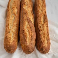 three long bread sticks sitting on top of a white cloth