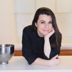 a woman sitting at a table with a silver bowl on the counter next to her