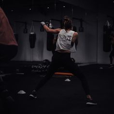 a woman is practicing boxing in the dark with her hands up and one arm out