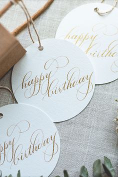 three white and gold happy birthday tags sitting on top of a table