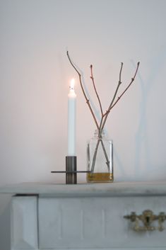 two candles sitting on top of a white dresser