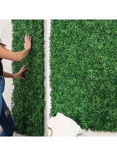 a woman standing in front of a fake grass wall with her hands on the ground