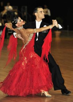 a man and woman in ballroom attire dancing on a dance floor with their arms around each other