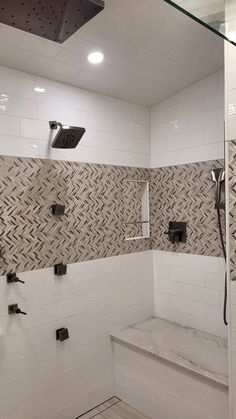 a bathroom with white tiles and black fixtures on the shower head, hand held faucet