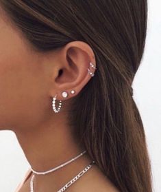 a close up of a woman wearing two different necklaces and earring sets on her neck