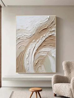 an abstract painting hangs on the wall next to a chair and footstool in a living room