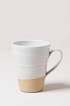 a white and tan coffee cup sitting on top of a table