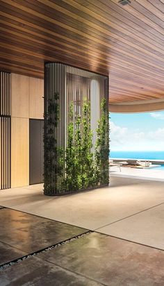 an open room with wooden walls and plants on the wall, overlooking the ocean in the distance