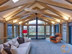 a living room filled with furniture next to a tall wooden ceiling covered in glass windows