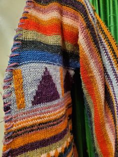 a multicolored scarf hanging on a green curtain