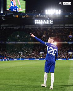 a man standing on top of a soccer field in front of a large screen tv