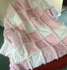 a pink and white crocheted blanket sitting on top of a table