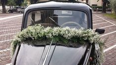 an old black car is decorated with flowers and greenery