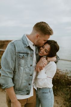 a man and woman hugging each other by the water