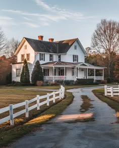 a large white house sitting on top of a lush green field next to a road