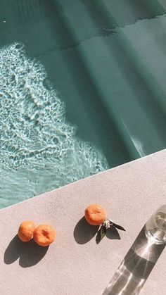 three donuts sitting on the edge of a swimming pool next to a bottle of water