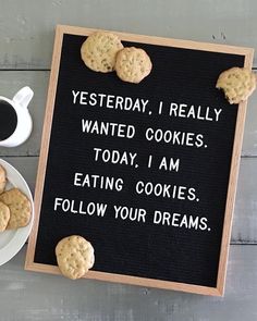 a sign with cookies on it next to a cup of coffee and a plate of cookies