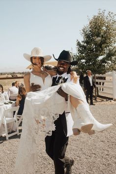 a man in a cowboy hat holding a woman wearing a white dress and black pants