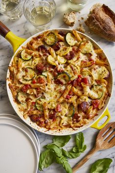 a pizza with zucchini, tomatoes and other toppings on a marble table