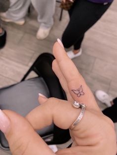 a person with a small butterfly tattoo on their finger