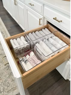 an open drawer in the middle of a kitchen with towels and other items inside it