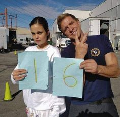 a man and woman holding up two pieces of paper with the number six on it