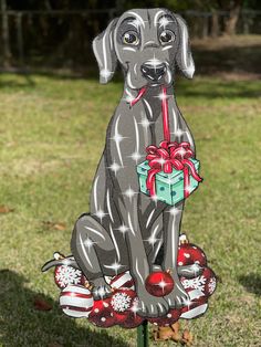 a black dog sitting on top of a christmas ornament with a present in it's mouth