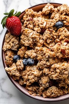 a bowl filled with granola and blueberries on top of a marble countertop