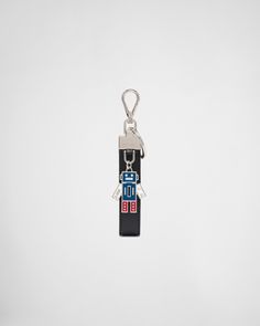 a keychain shaped like a robot is hanging from a hook on a white background