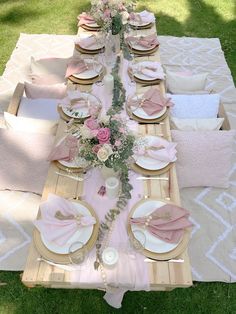 the table is set with pink and white plates, napkins, and place settings