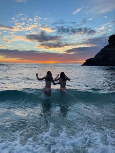 two women are in the ocean at sunset