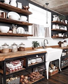 a kitchen filled with lots of open shelves next to a white sink and wooden counter top