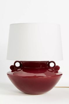 a lamp that is sitting on top of a white table cloth next to a red bowl