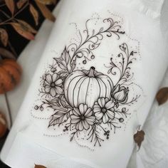 a white napkin with a pumpkin and flowers design on it next to some fall leaves