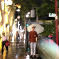 people walking down the street with umbrellas on a rainy night