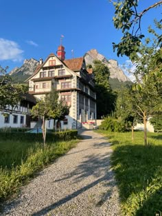 an old house in the mountains with a gravel path leading up to it's front door