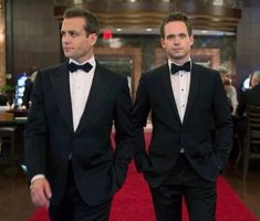 two men in tuxedos walking down a red carpet