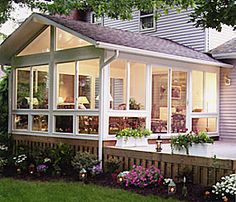 a house that has some flowers in the front yard and on the side of it