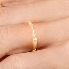 a woman's hand wearing a gold ring with three diamonds on the middle and sides