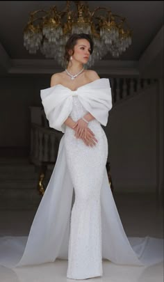 a woman in a white gown with a long veil on her head and hands behind her back