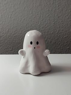 a white ghost figurine sitting on top of a table next to a wall