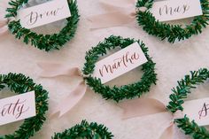 small wreaths with name tags on them sitting on a white tablecloth covered floor