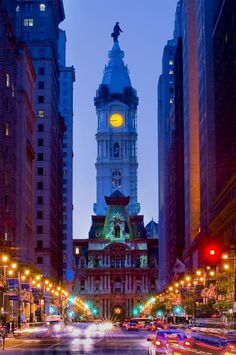 a large clock tower towering over a city filled with tall buildings and traffic at night