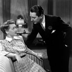 a man standing next to a woman on top of a couch